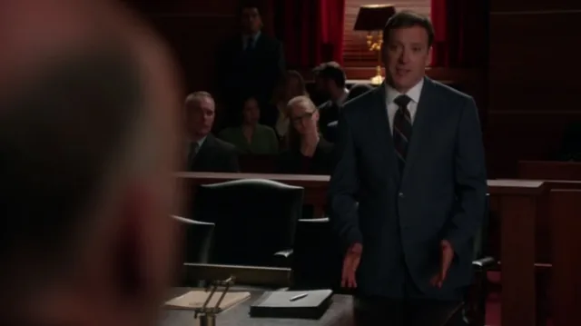 A still from The Good Wife: a man in a suit in a dim room