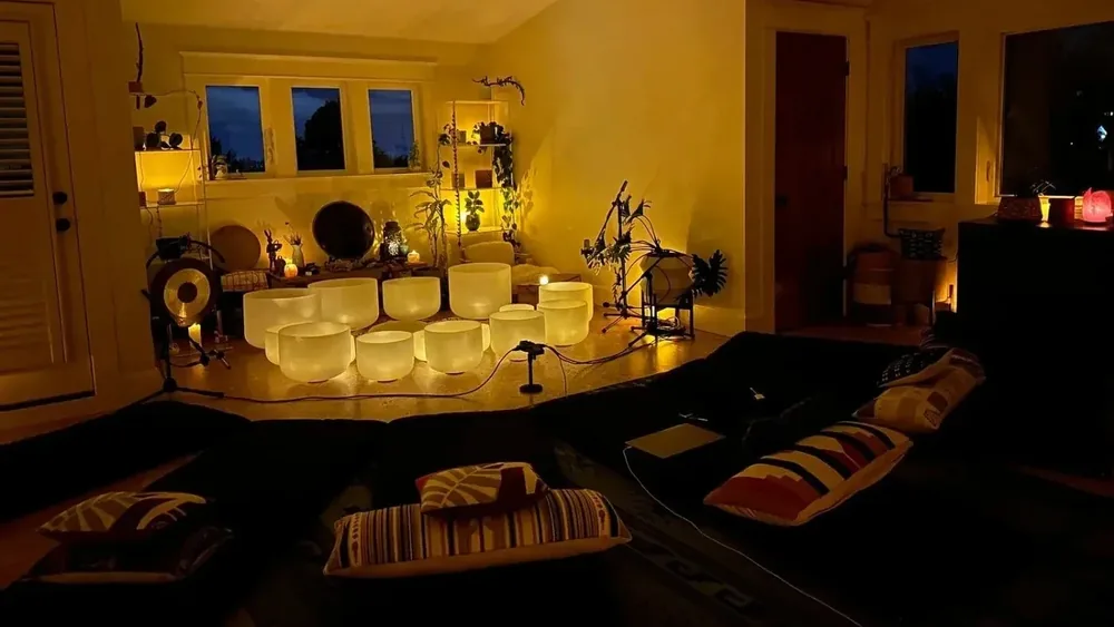 The Attic, Aloka’s private studio: dormer windows at dusk, warm lamps, a ring of crystal bowls on a rug