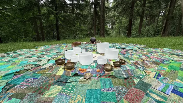 Crystal and Tibetan bowls on patchwork quilts in a clearing ringed by fir trees