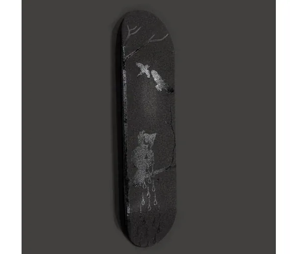 A black skateboard deck painted with a pale crying figure
