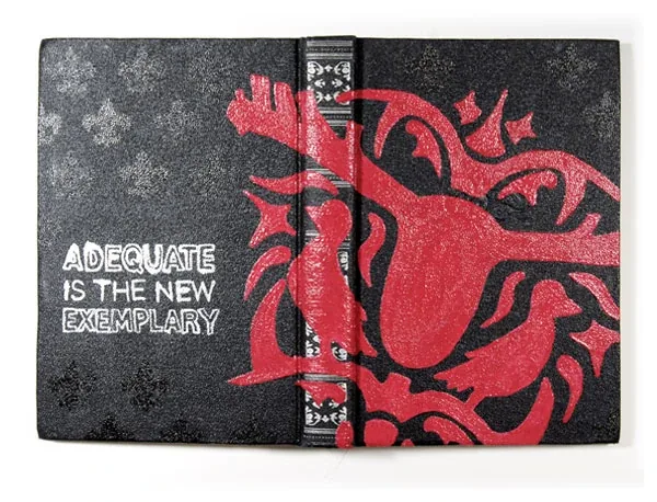 A black book painted with a red creature and the words Adequate is the new exemplary