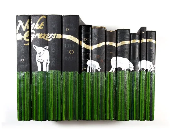 A row of black book spines painted with white sheep grazing on green