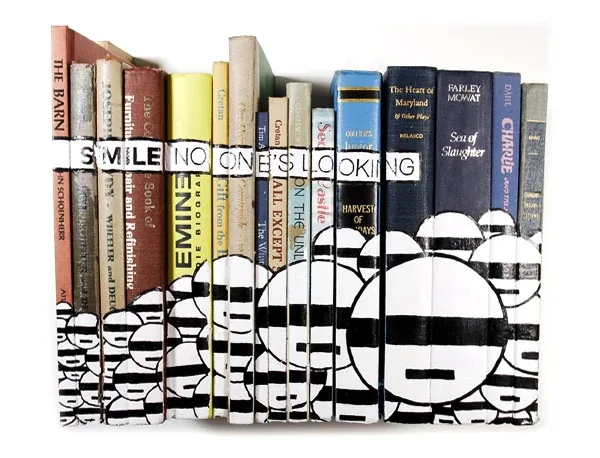 A shelf of books, their spines painted with black and white striped faces