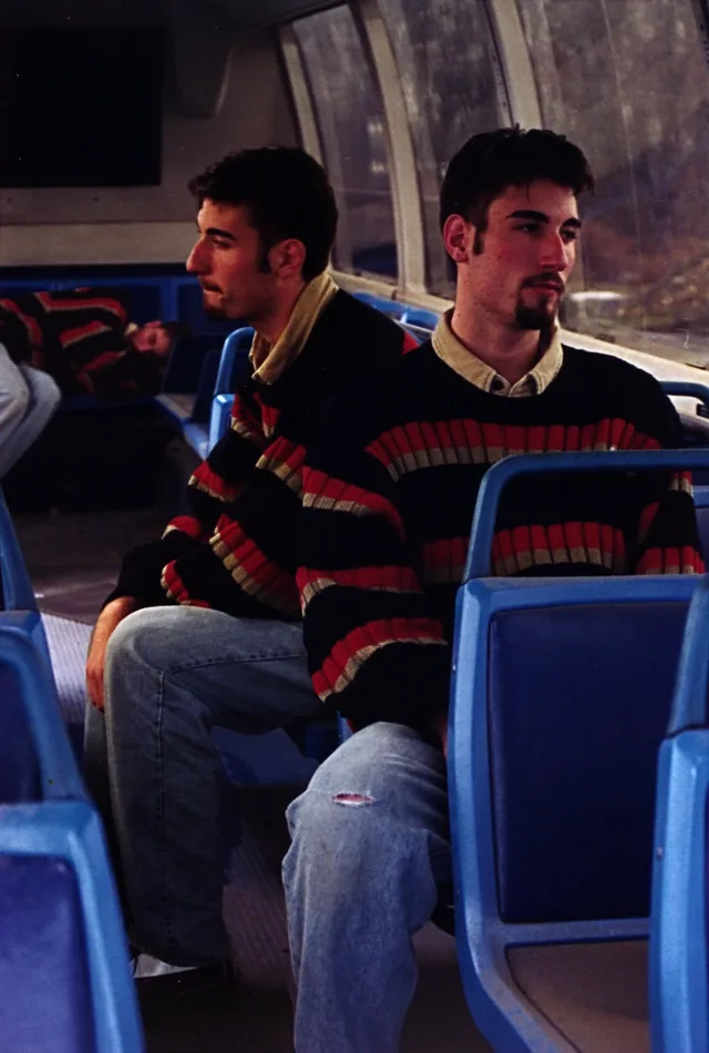 Two young men in matching striped sweaters on a bus
