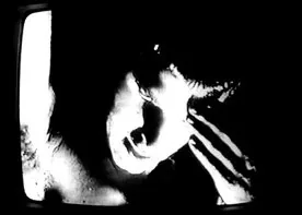 A hand over a face on a television screen, in stark black and white