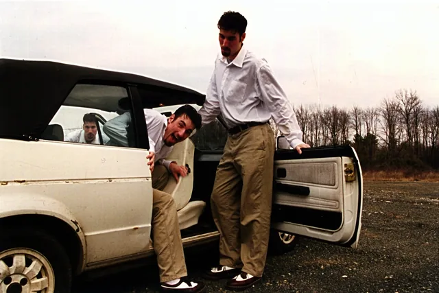 Two men climbing out of a white convertible