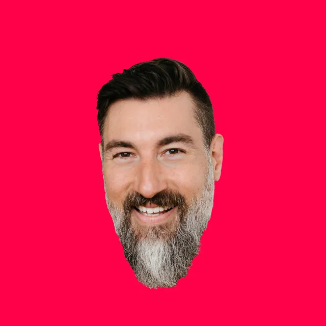 Graham’s head, cut out of a photograph, smiling broadly, with dark swept-back hair and a full beard going gray at the chin, on a hot red square