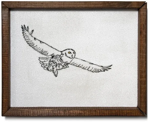 A snowy owl in flight over white, in a dark wood frame