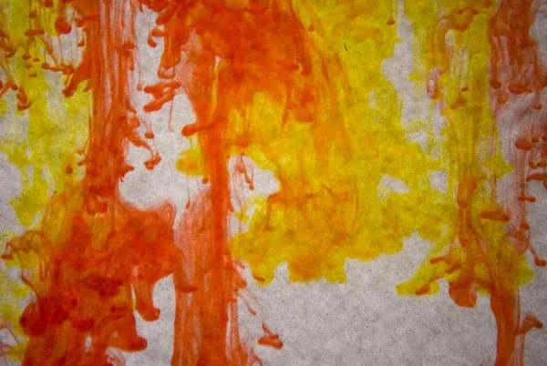 Orange and yellow ink streaming down through water