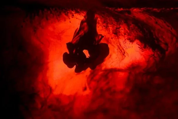 Black ink drifting through glowing red