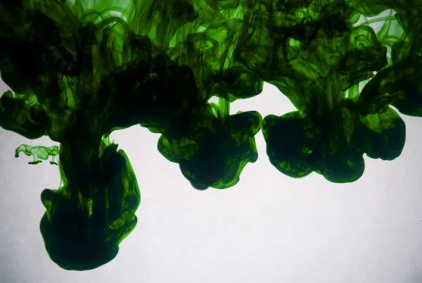 Dark green ink falling in a line of plumes
