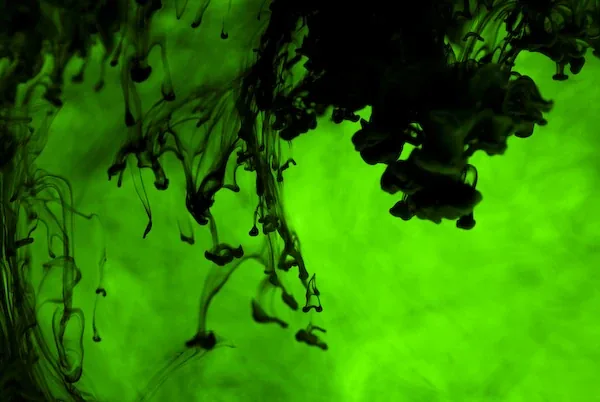 Black ink drifting down through bright green
