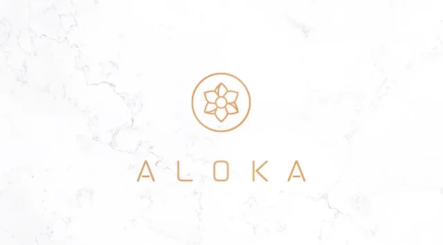 The Aloka logo: a copper lotus above the word ALOKA, spaced wide, on white marble