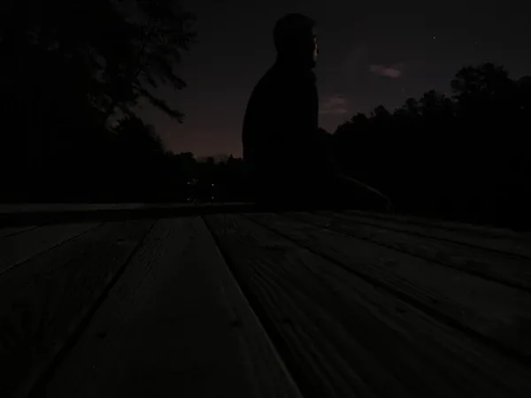 A figure in silhouette on a dock at night
