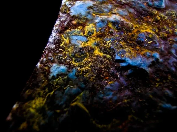 A dark curve across a mottled surface of blue, gold and purple