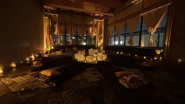A candlelit pop-up room with tall windows, crystal bowls on the floor and mats laid out