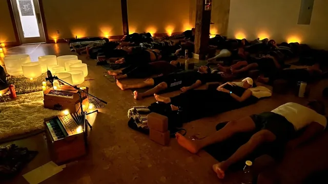 People resting on mats at Wild Reed Yoga, crystal bowls and a harmonium glowing in candlelight