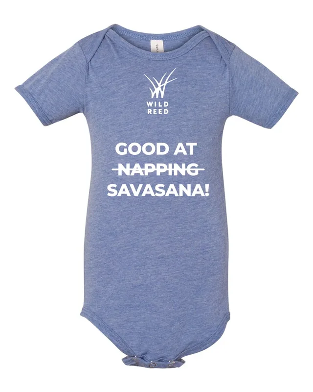 A heather blue baby onesie: the white logo, then GOOD AT, NAPPING crossed out, SAVASANA!